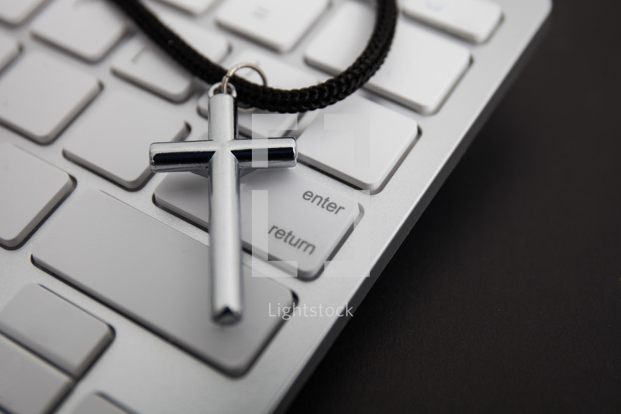 silver cross on a lanyard on a computer keyboard 