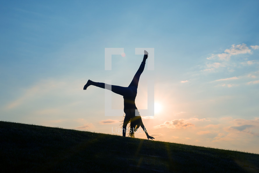 a silhouette of a woman doing a cartwheel 