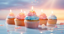Cupcakes with buttercream frosting and burning candles on blue background