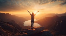 Happy woman standing on top of mountain and looking at beautiful sunset sky