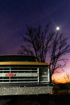 moon above an old yellow truck 