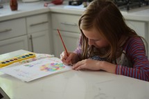 a girl painting a happy birthday card 