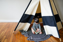 a toddler girl playing in a play tent 