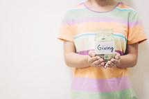 a child holding a giving jar full of money 