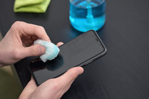 Man Cleaning Smartphone Screen With Alcohol Or Disinfectant