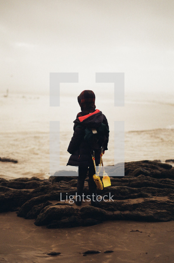 child in a coat on a beach 