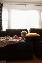 toddler lying on a couch using an iPad 