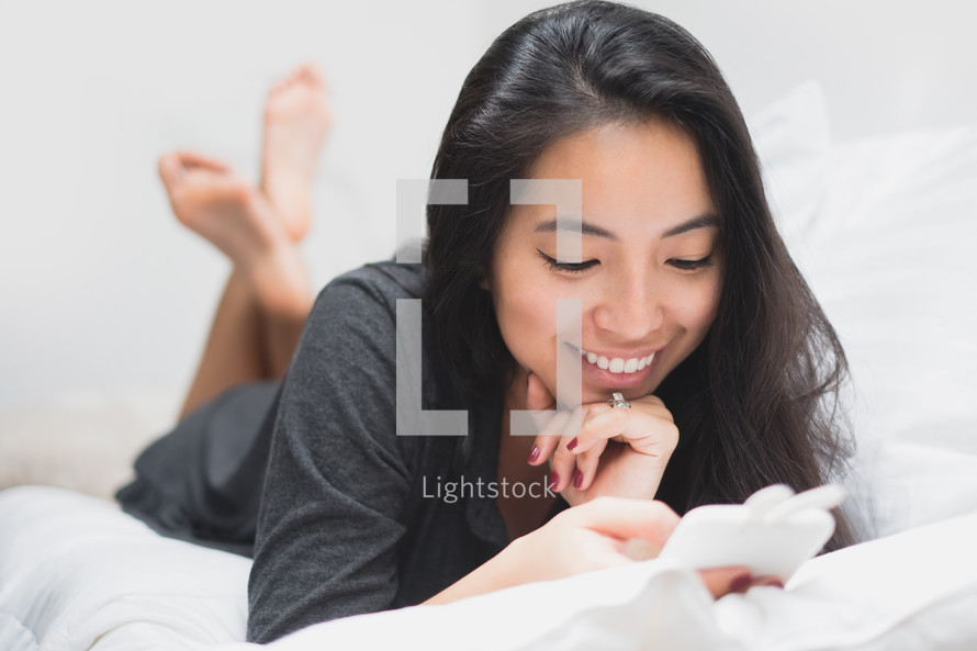 woman on a bed checking her cellphone 