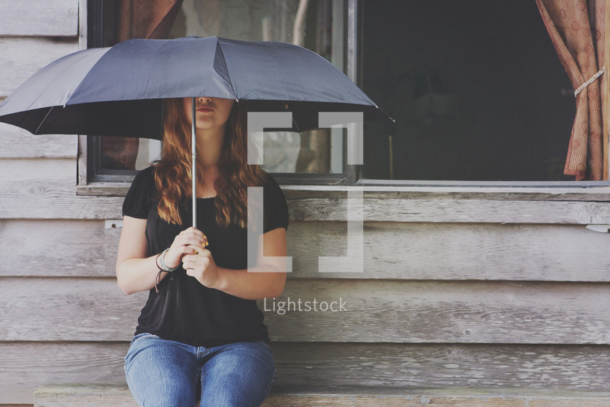 a girl sits alone with umbrella