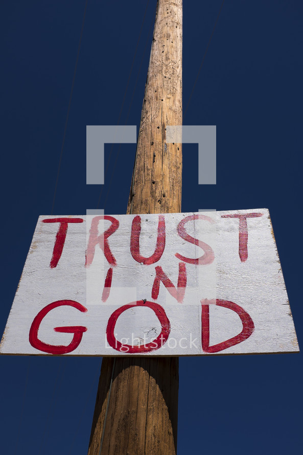 "Trust in God" sign nailed to a telephone pole.