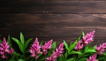 Pink flowers on a brown wooden background. Top view with copy space.