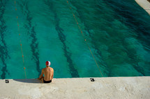 swimmer sitting at the edge of a pool