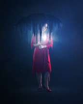 a woman standing under an umbrella in darkness 