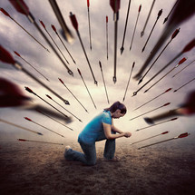 woman is all alone and in prayer as she is surrounded by many arrows