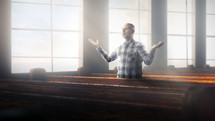 A man stands in praise alone in a church.