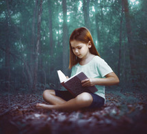 A young girl reads alone in the dark forest