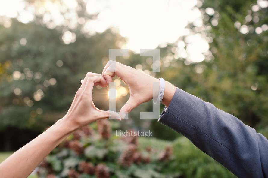 couple forming a heart shape with their hands 