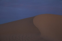 A windswept ridge on a sand dune at dusk
