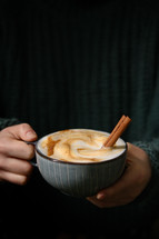 Woman holding Cup of cappuccino with Cinnamon Sticks