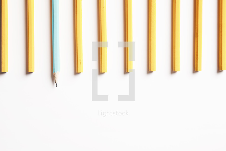 row of unsharpened pencils with one blue pencil sharpened. 