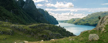 Sheep along the meadow in a large valley in Stavanger, Norway, with mountains and a lake, 