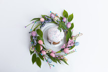 Easter cake in the center of a wreath of spring flowers on a blue vintage background