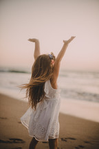 a girl on a beach with raised hands 
