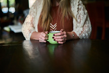 a woman in a sweater drinking coffee 