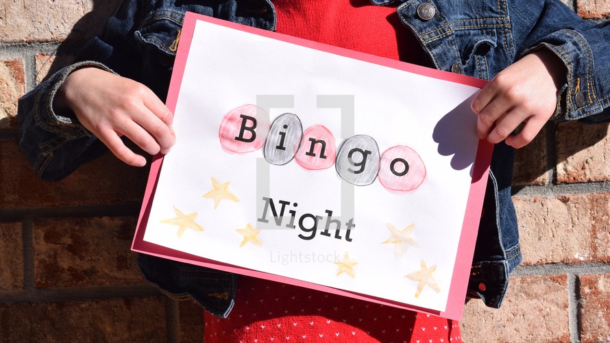 A little girl holding a Bingo Night sign 
