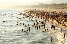 people in the ocean on a crowded beach 