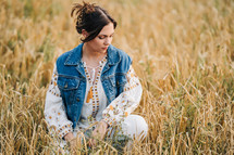 attractive hippy woman on nature background. Young lady in white embroidery shirt, denim waistcoat. Summer fashion, hipster, ethno, folk lifestyle.