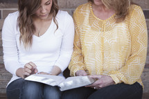 A mother and daughter reading a Bible together 