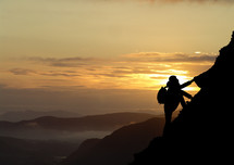 Man climbing a mountain at sunset with scenic view