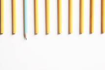 row of unsharpened pencils with one blue pencil sharpened. 