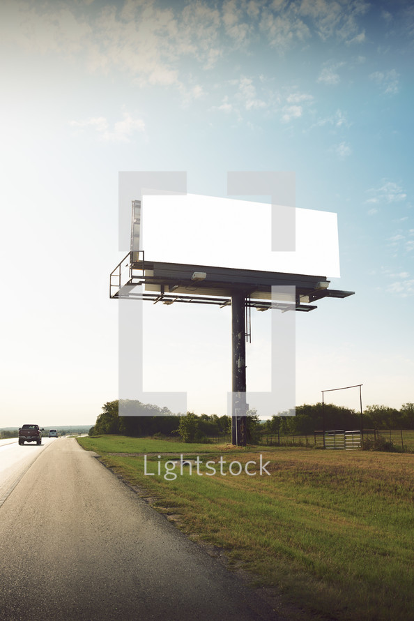 a car passing a blank billboard 