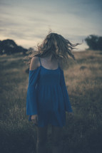 A woman in a blue dress walking through a field.