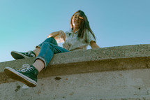 teen girl sitting on a concrete wall 