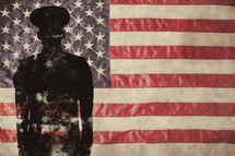 Silhouette of a solder standing in front of an American flag.