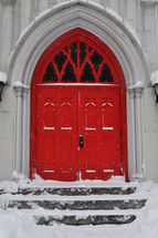 Red church doors stand out in the snow.