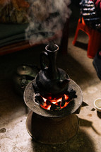 Ethiopian coffee pot sitting on hot coals for a coffee ceremony