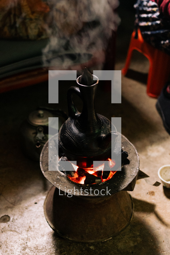 Ethiopian coffee pot sitting on hot coals for a coffee ceremony