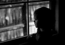 toddler girl looking out a window 