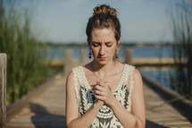 girl praying by a lake 