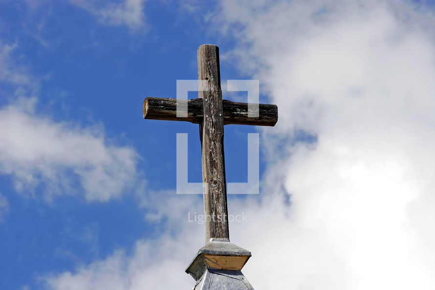 Rugged Cross on a Steeple - A large rugged cross atop a country church is highlighted against a summer sky.  The empty cross shows "He is risen!"