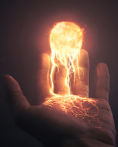 A hand holding the sun with burning streams of light and lava.