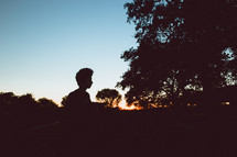 silhouette of a boy outdoors at dusk 