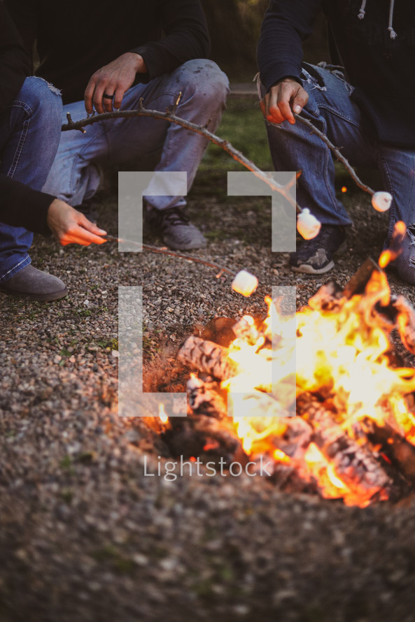 men roasting marshmallows around a fire 