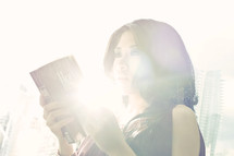 Woman reading glowing Bible.