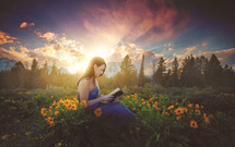 a woman reading a Bible in a field of wildflowers 