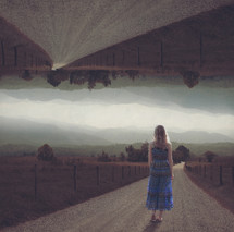 a woman standing in the middle of a gravel road